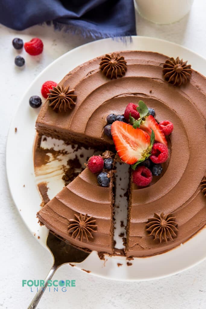 Top down view of a chocolate cake with a slice removed and berries in the center.