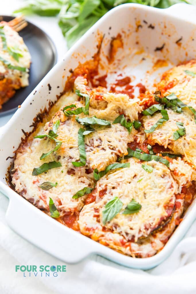 a rectangle baking dish of eggplant parmesan, missing one serving.