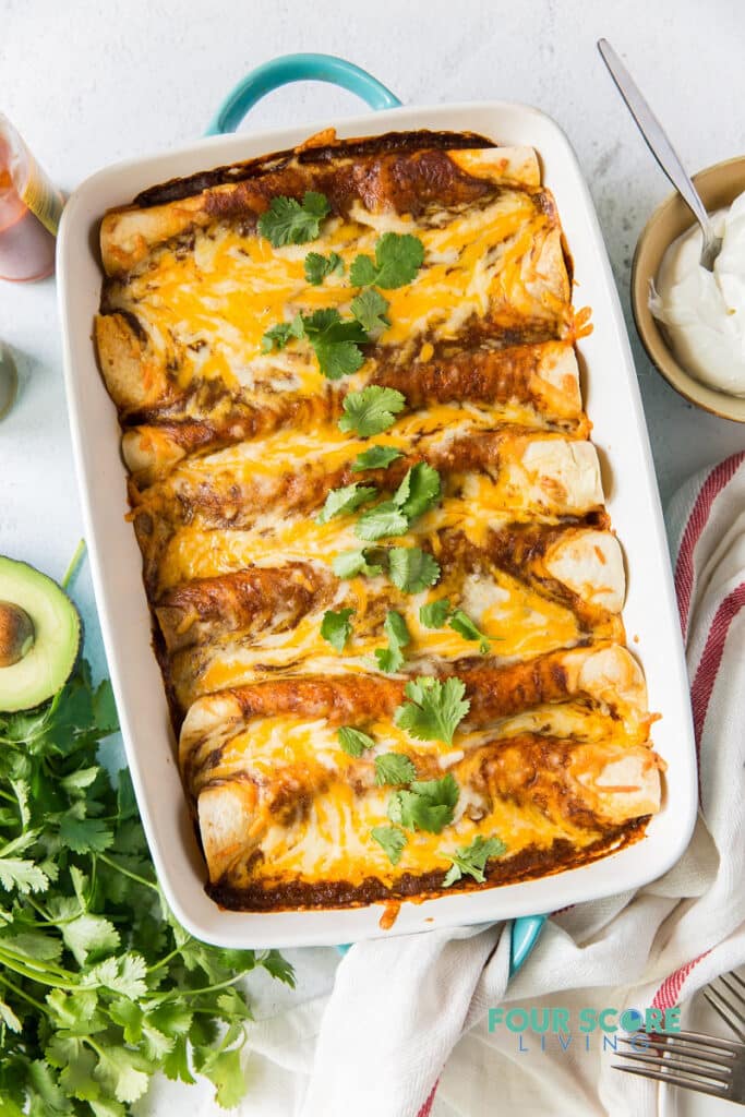 a full pan of enchiladas topped with melted cheese and cilantro garnish.