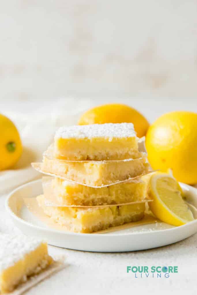 a plate of 4 leman bars, stacked on top of each other, surrounded by lemons.