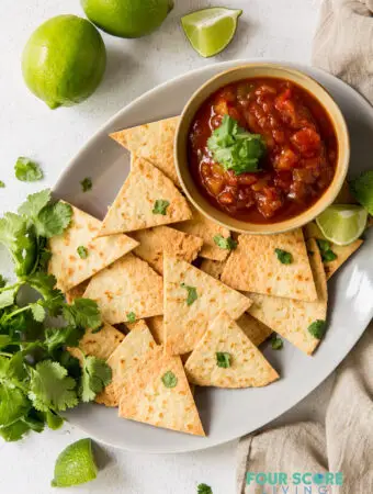 a tray of chips and salsa garnished with lime wedges and cilantro.
