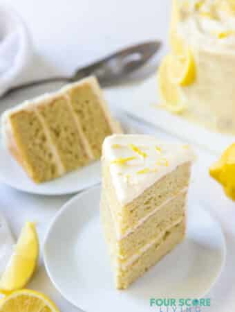 Two plates each with a three layer slice of lemon cake.