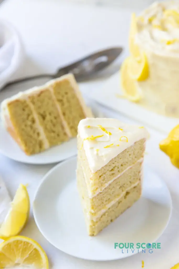 Two plates each with a three layer slice of lemon cake.