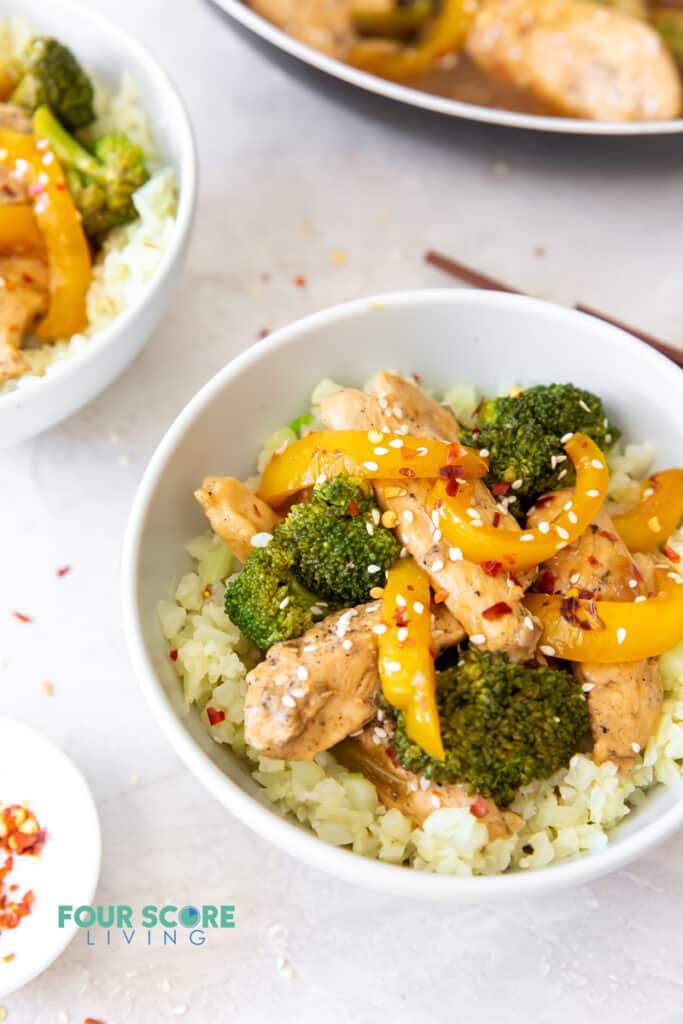 a bowl of chicken, broccoli, and pepper stir fry on top of cauliflower rice.