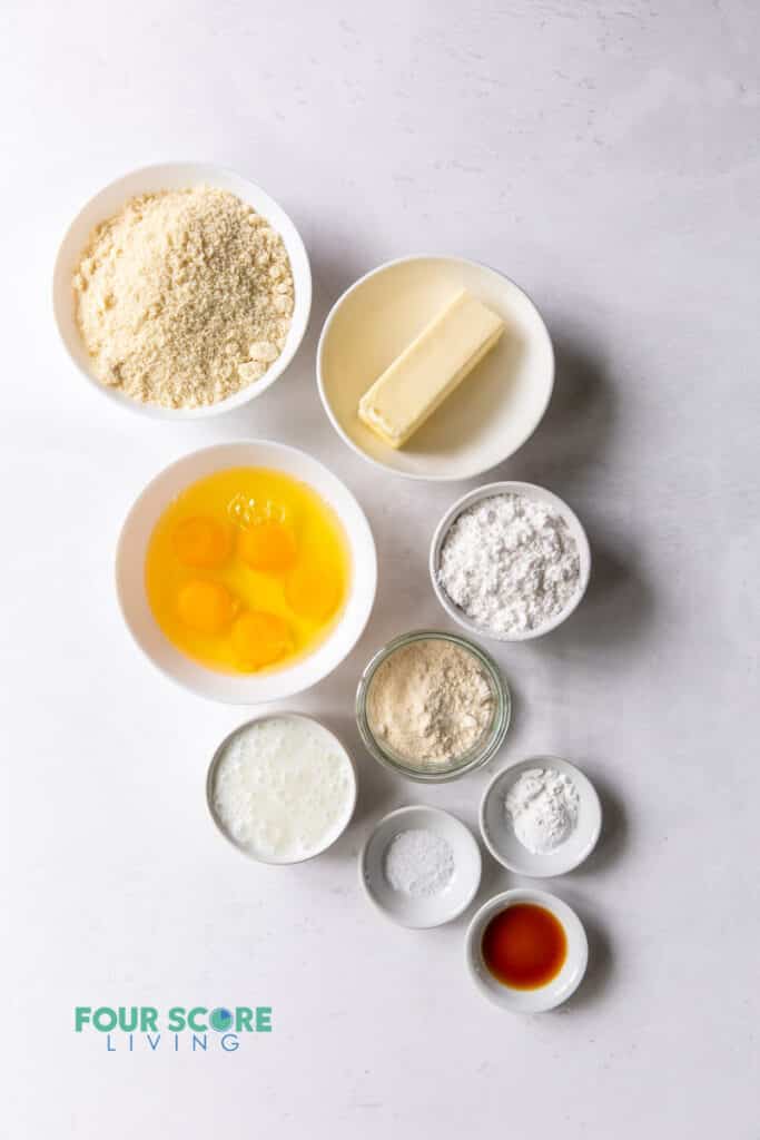 Top down view of ingredients for keto vanilla cake including eggs, flours, butter, and others.