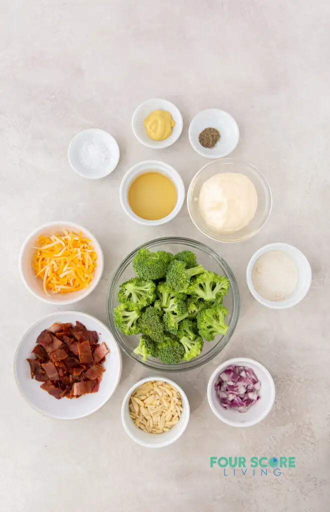 top down view of the ingredients needed to make keto broccoli salad including broccoli, cheese, onion, seasonings, and mayonnaise