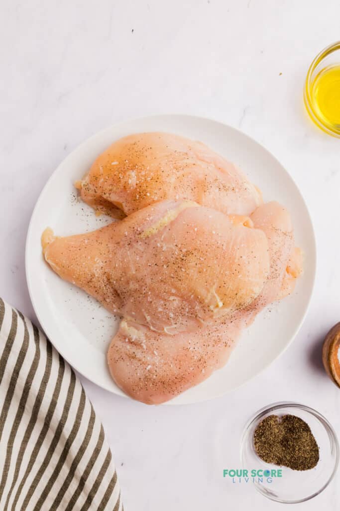 raw chicken on a white plate next to a striped napkin