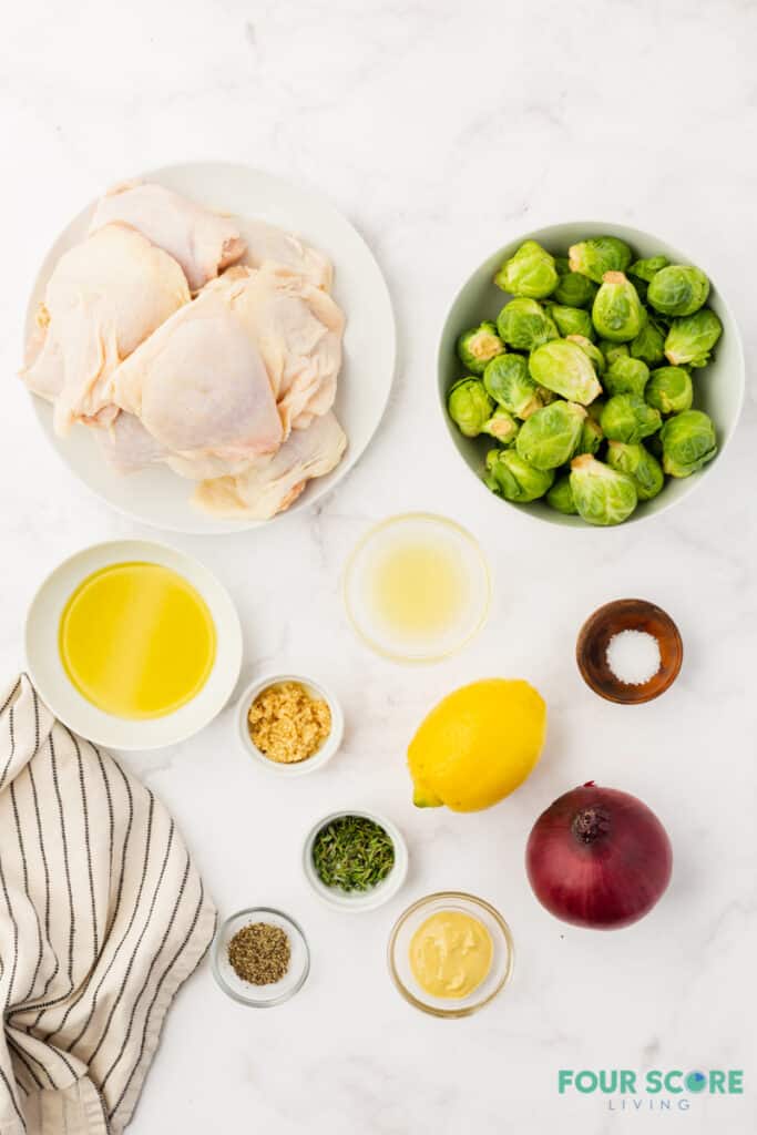 ingredients for making chicken and brussel sprouts measured into separate bowls on a marble counter