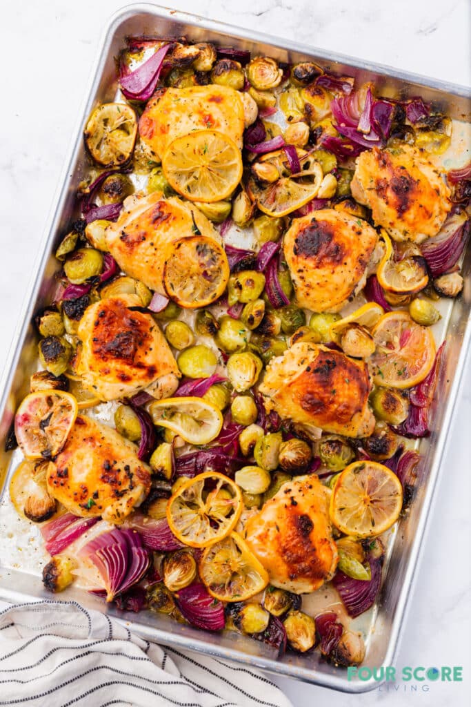 sheet pan chicken and brussels sprouts with sliced lemons and red onion