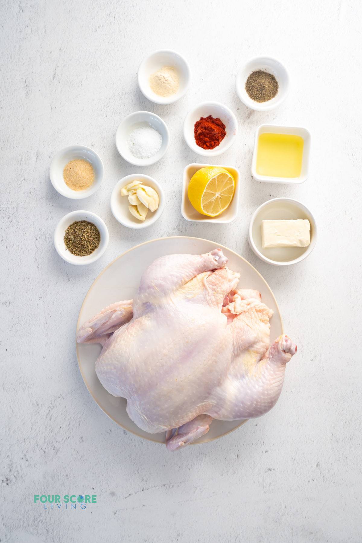 Ingredients for making a whole chicken in the instant pot in separate bowls on a countertop. Includes lemon, butter, garlic, and seasonings