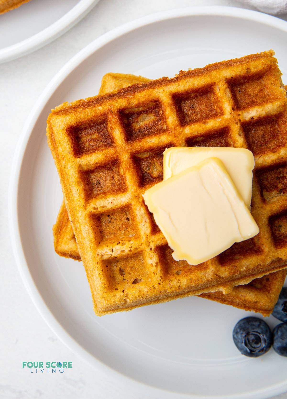 a stack of two keto waffles topped with two pats of butter.