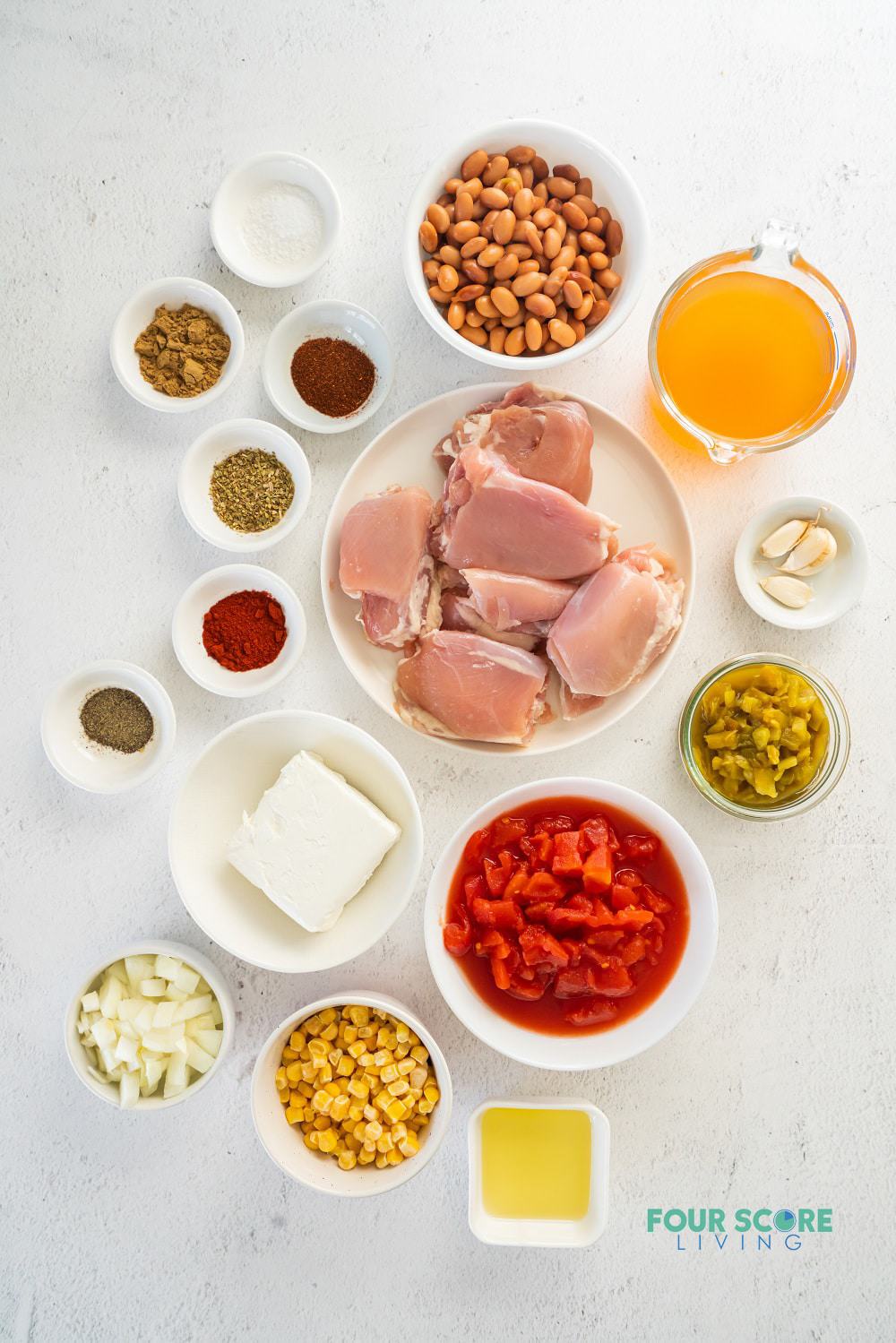 The ingredients for making white chicken chili in separate bowls on a countertop, viewed from above.