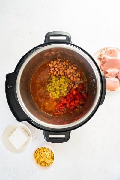 Top view photo of the Instant Pot with diced tomato, beans, and green chiles added to the pot.