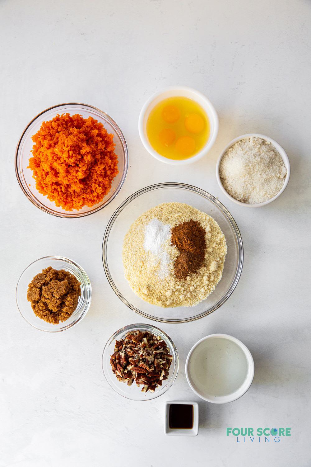 The ingredients needed to make a keto carrot cake, measured into separate small bowls.