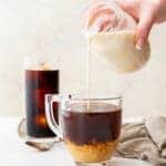 almond milk creamer being poured into a cup of coffee