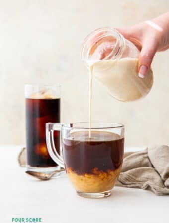 almond milk creamer being poured into a cup of coffee