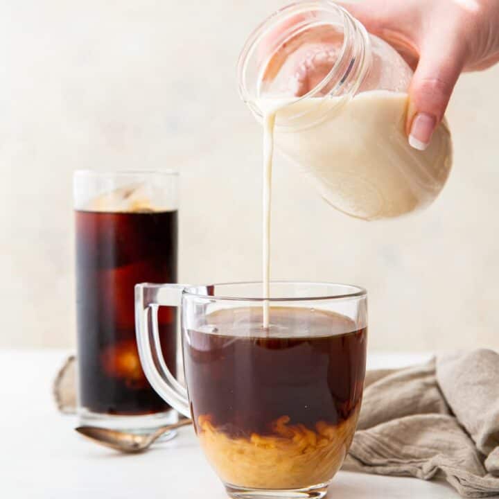 almond milk creamer being poured into a cup of coffee