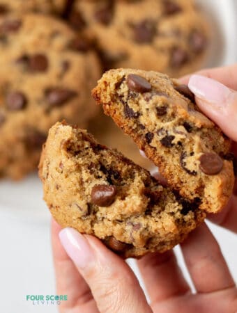 hand breaking apart a almond flour chocolate chip cookie