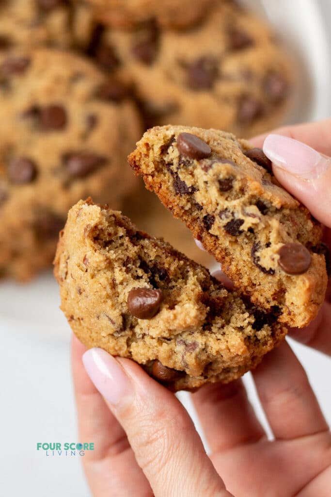 hand breaking apart a almond flour chocolate chip cookie