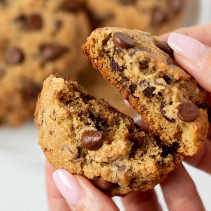 hand breaking apart a almond flour chocolate chip cookie