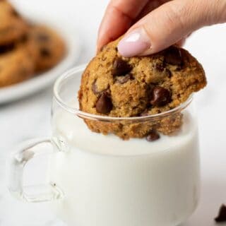 hand dipping keto chocolate chip cookie in milk