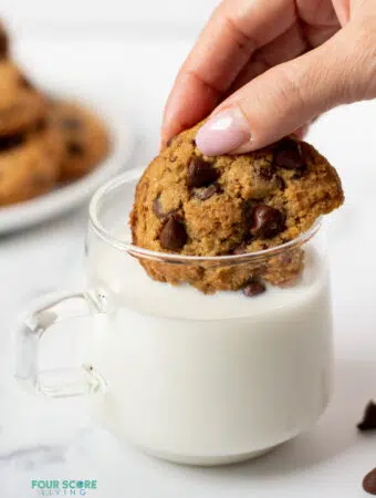 hand dipping keto chocolate chip cookie in milk