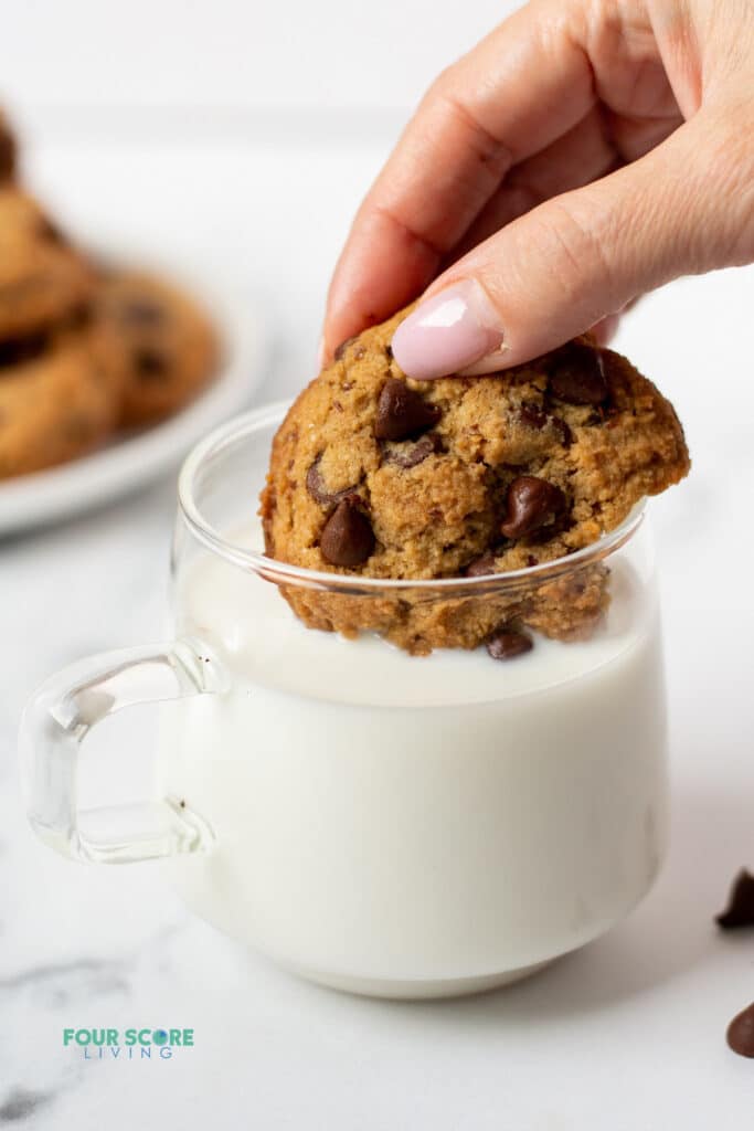 hand dipping keto chocolate chip cookie in milk