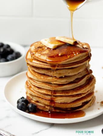 keto pancakes stacked on a white plate with a syrup drizzle