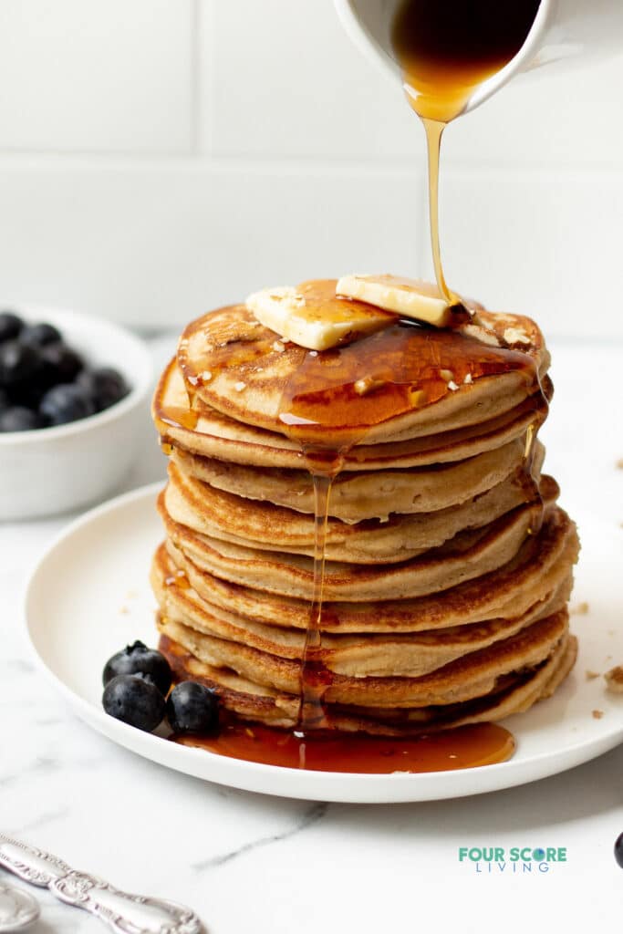 keto pancakes stacked on a white plate with a syrup drizzle