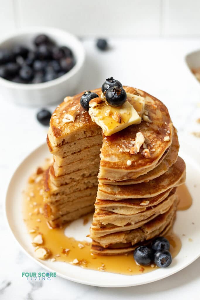 keto pancakes stacked on a white plate with a big bite taken out