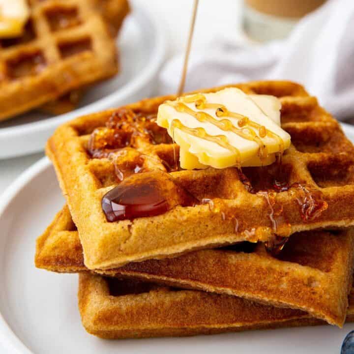 close up of a stack of 3 waffles with butter and syrup