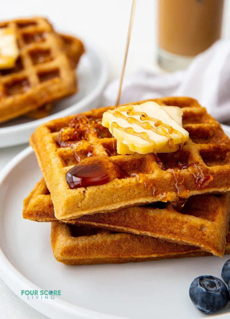 close up of a stack of 3 waffles with butter and syrup
