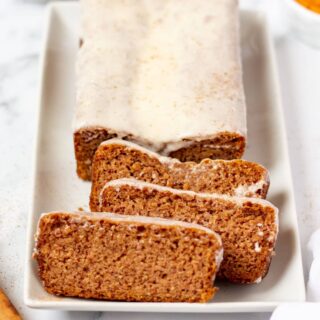 keto pumpkin bread with icing on a white plate