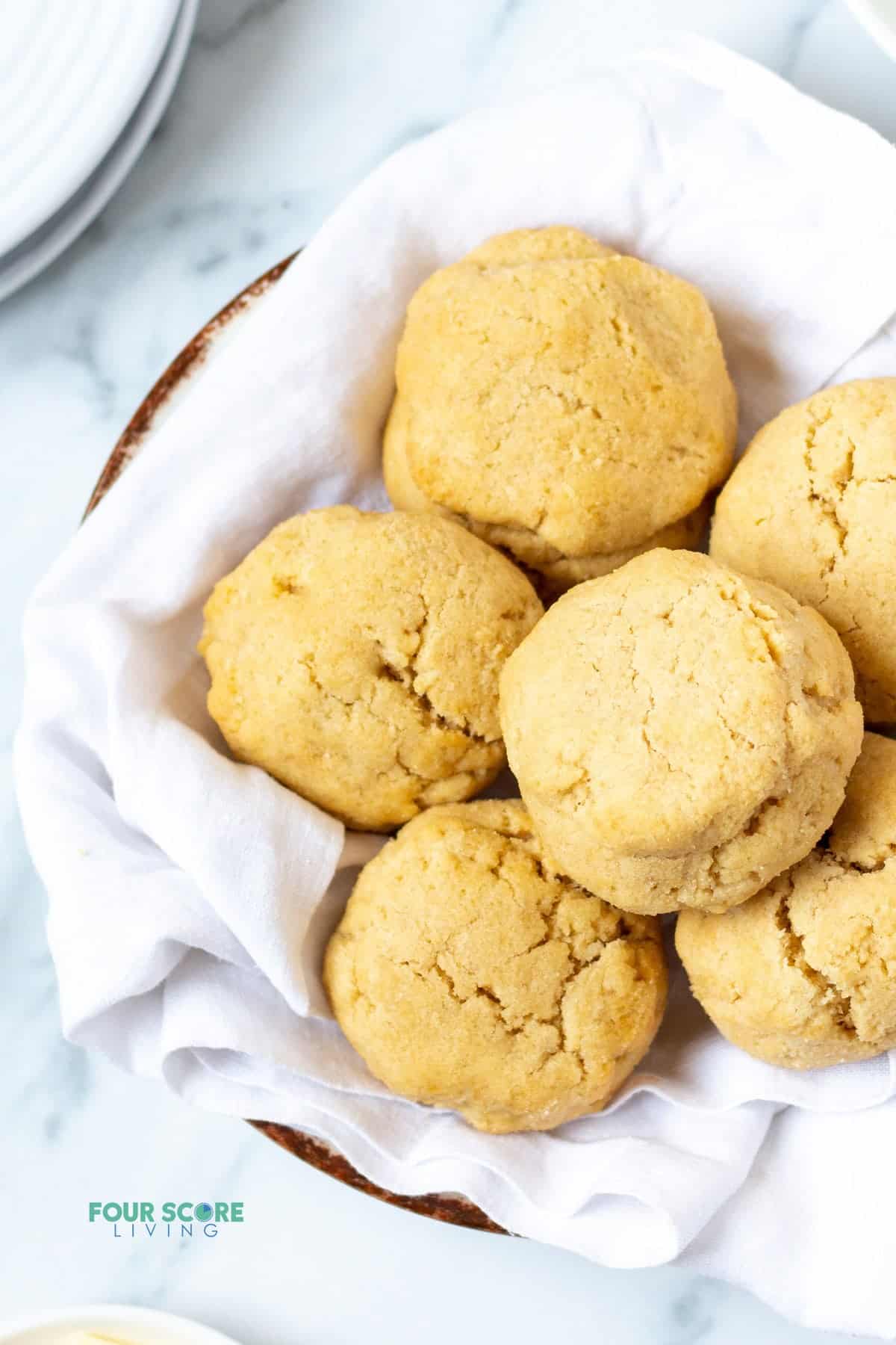 a bowl lined with a white tea towel filled with homemade almond flour biscuits