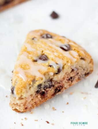 closeup view of a chocolate chip almond flour scone with drizzle of glaze.