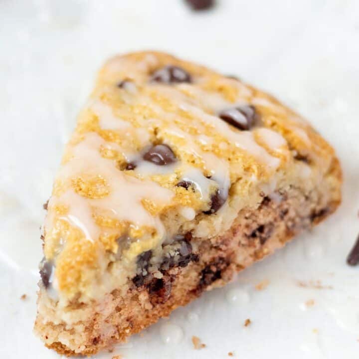closeup view of a chocolate chip almond flour scone with drizzle of glaze.