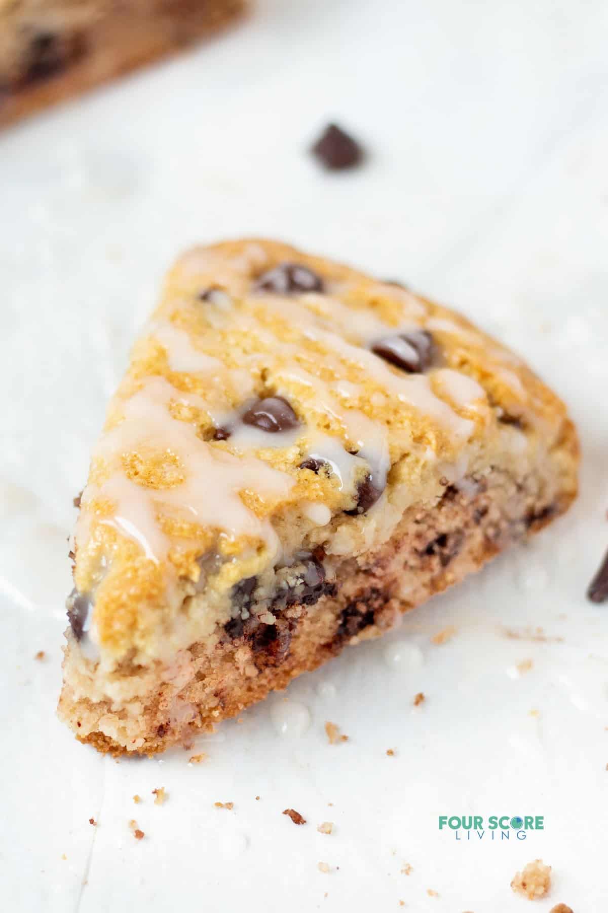 closeup view of a chocolate chip almond flour scone with drizzle of glaze.