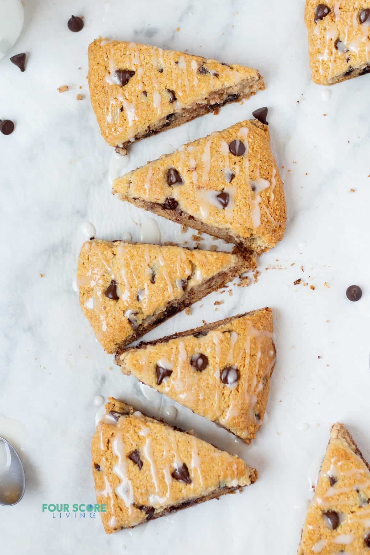 5 chocolate chip almond flour scones lined up vertically on a marble counter, viewed from above.