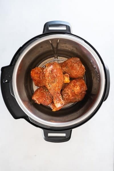 Top view photos of seasoned chicken legs inside the pot of the Instant Pot, and placed on the trivet.