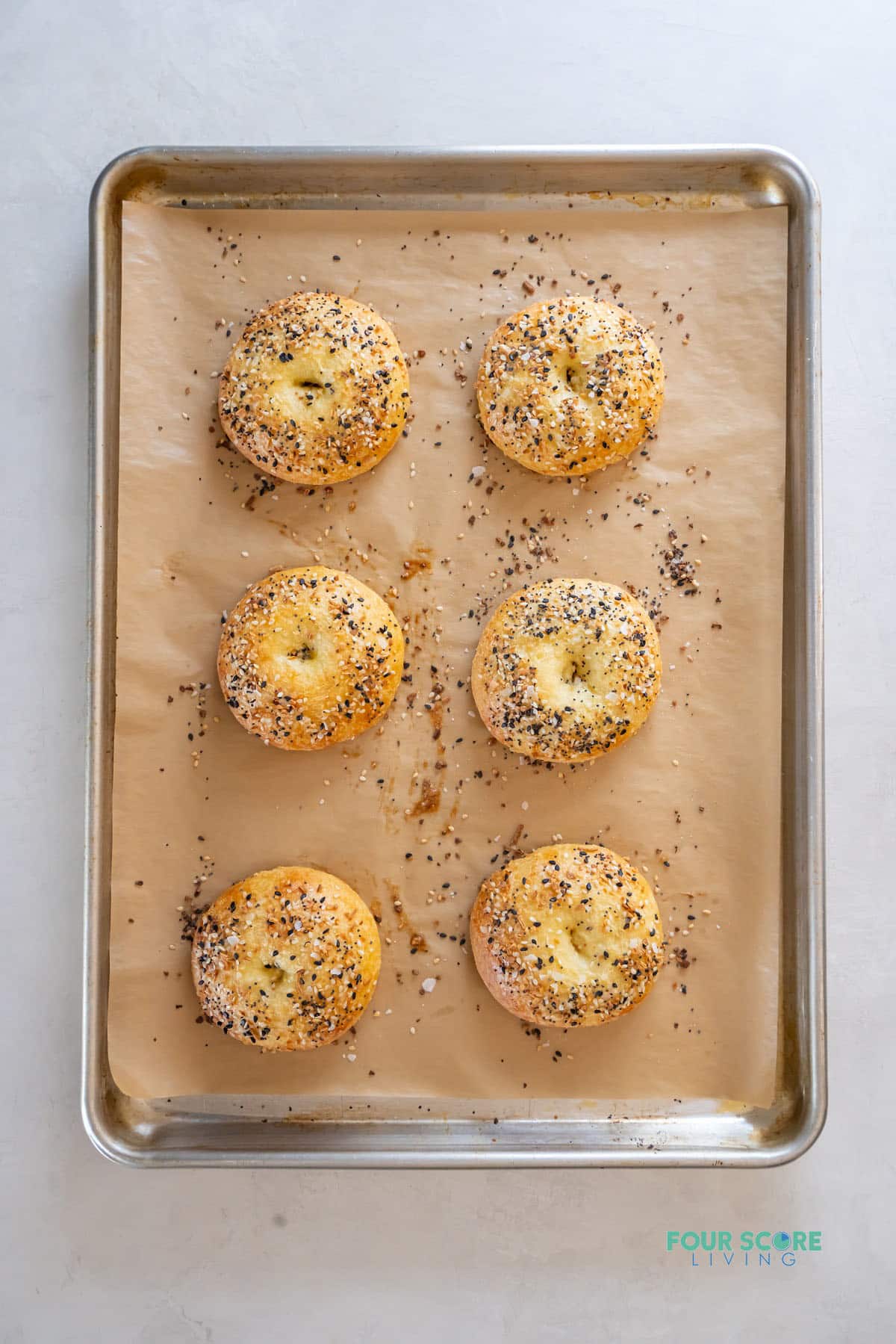 a sheet pan lined with parchment paper holding 6 baked keto everything bagels