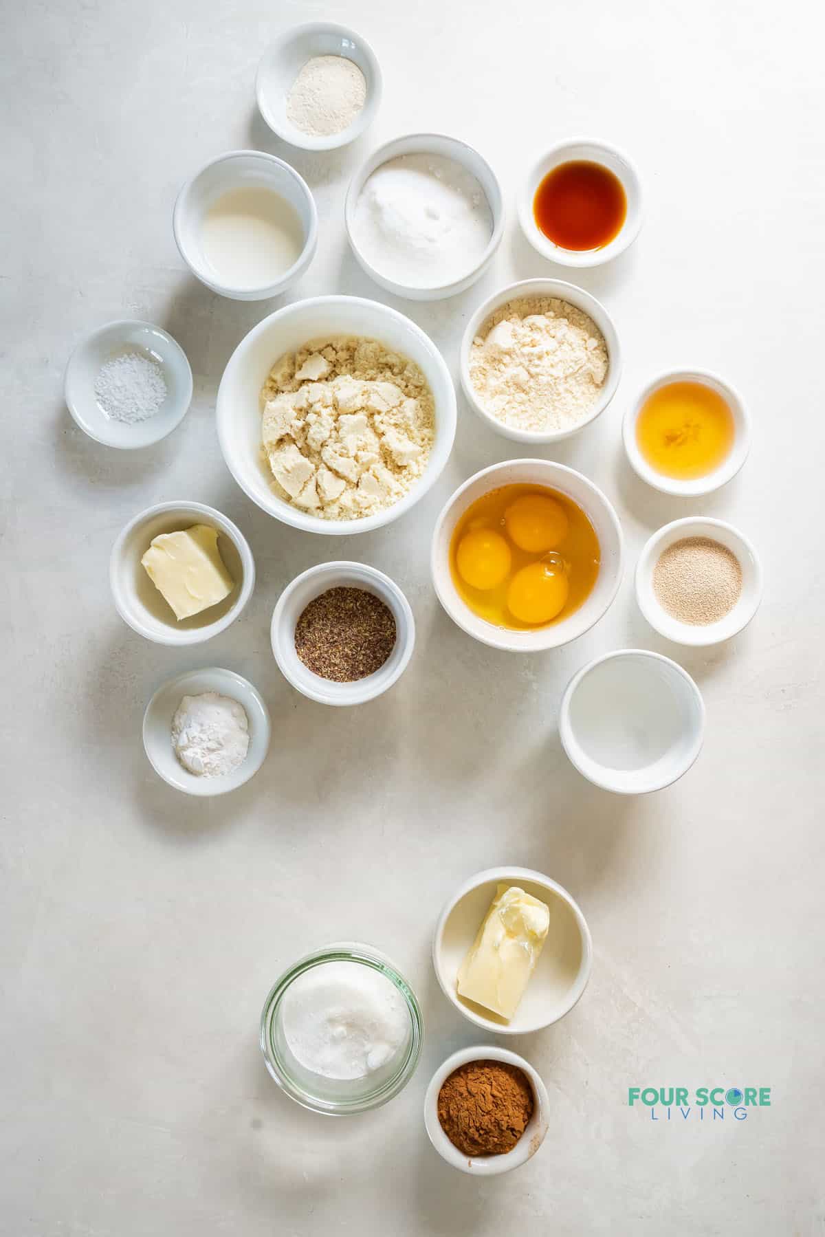 The ingredients needed to bake keto cinnamon rolls, all measured into small bowls on the counter, viewed from above.