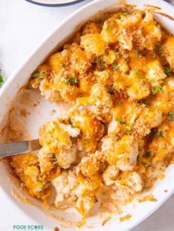 an oval casserole dish filled with keto cauliflower mac and cheese that has had a serving removed.