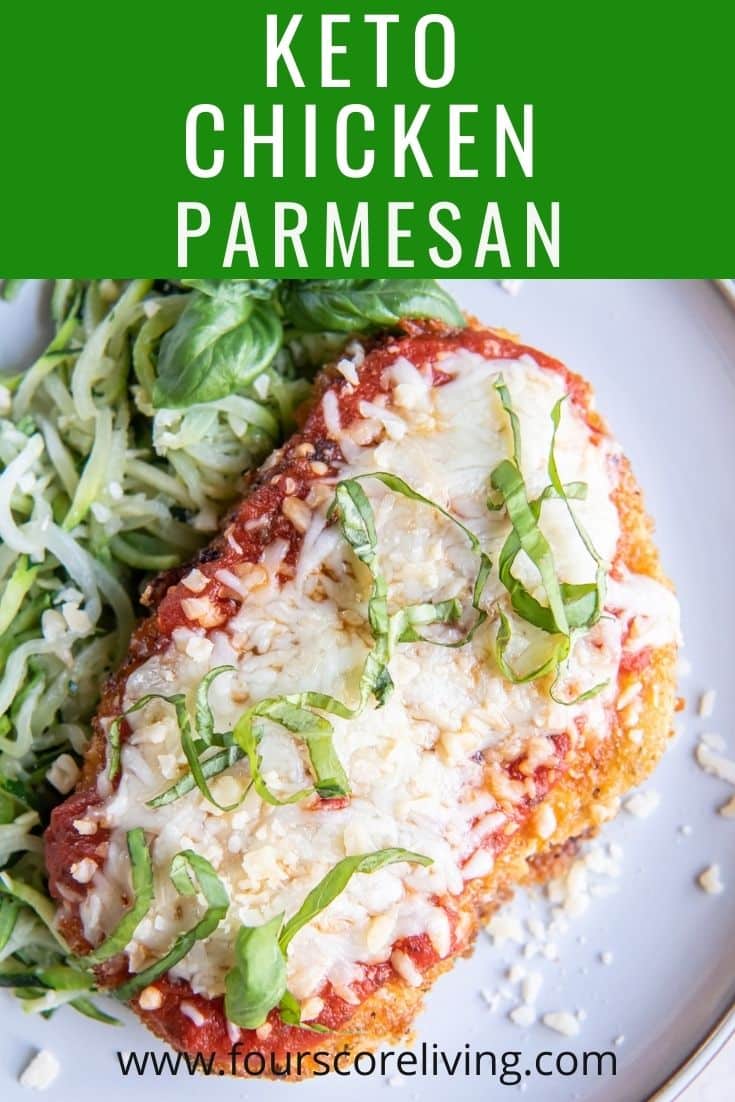 a keto chicken parmesan cutlet garnished with cut basil leaves, with a size of zoodles. Green box at top of image titles it, Keto Chicken Parmesan