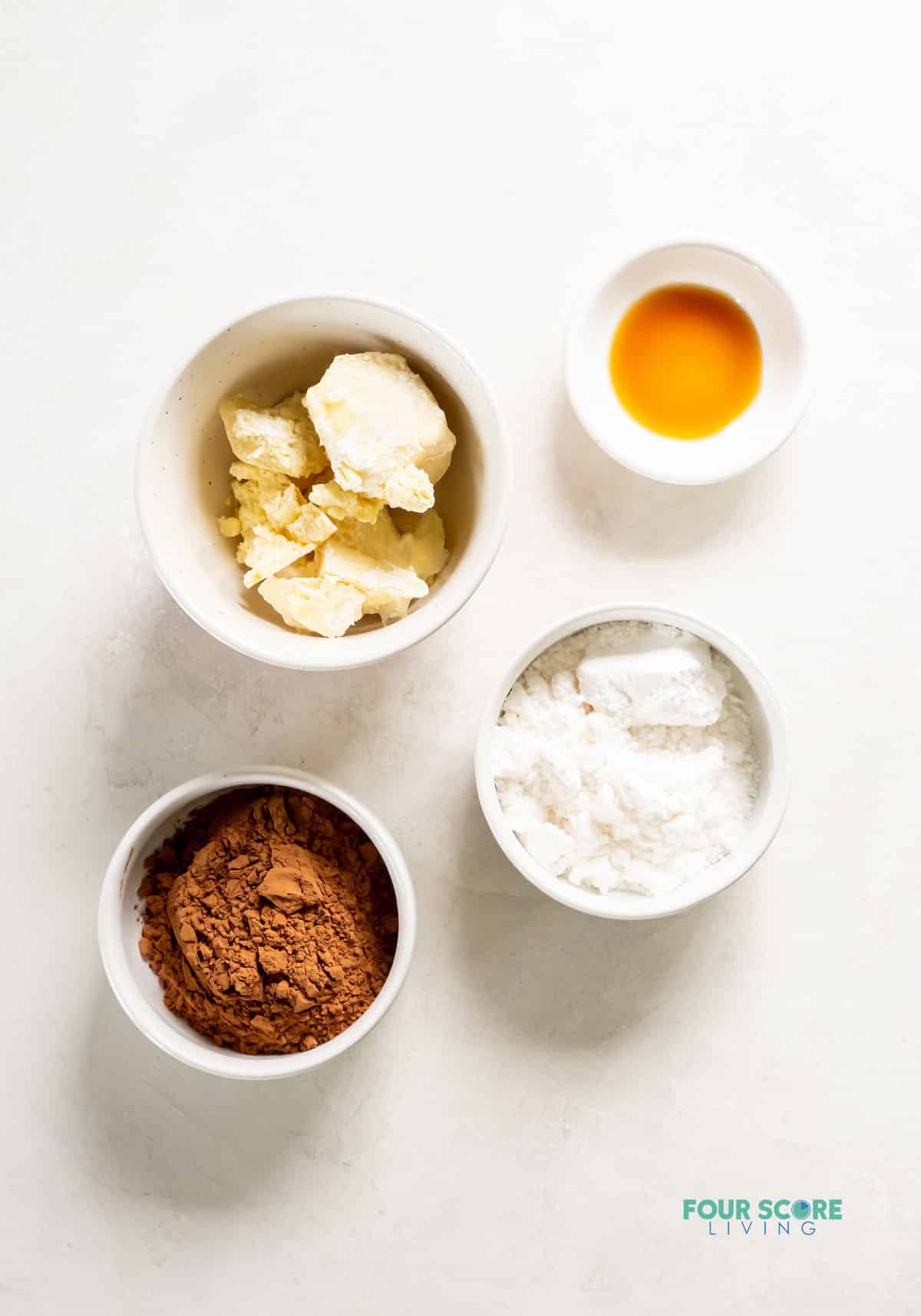 The ingredients for making keto chocolate chips, including cocoa butter, cocoa powder, vanilla, and powdered sweetener