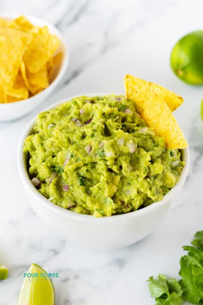 4 ingredient guacamole recipe in a white bowl with tortilla chips