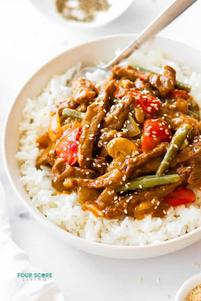 a bowl of rice with black pepper angus steak stir-fry on top