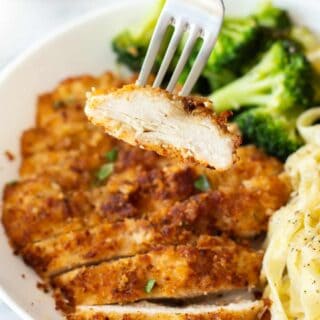 a fork holding up a piece of sliced chicken from our chicken fritta recipe