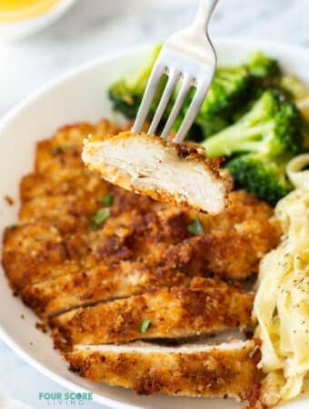 a fork holding up a piece of sliced chicken from our chicken fritta recipe