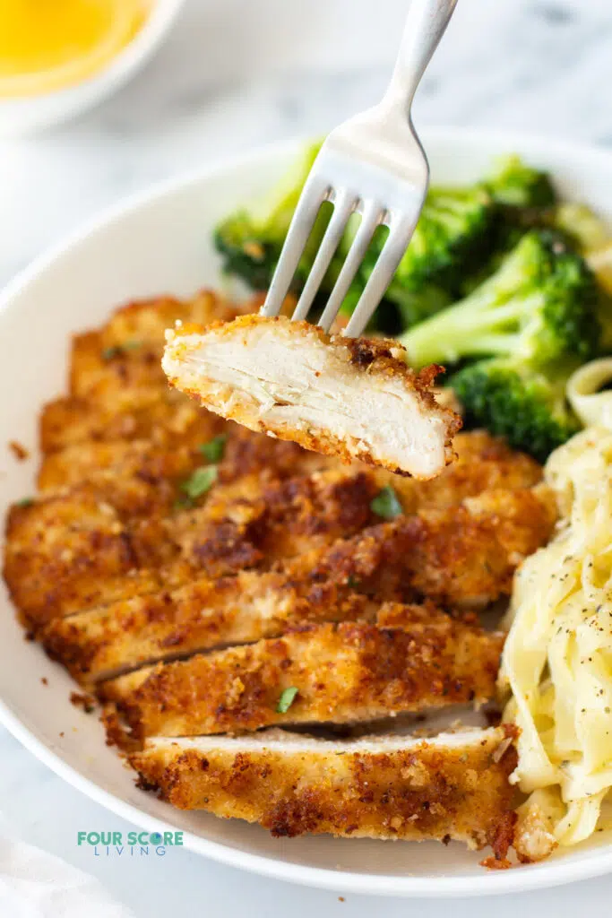 a fork holding up a piece of sliced chicken from our chicken fritta recipe