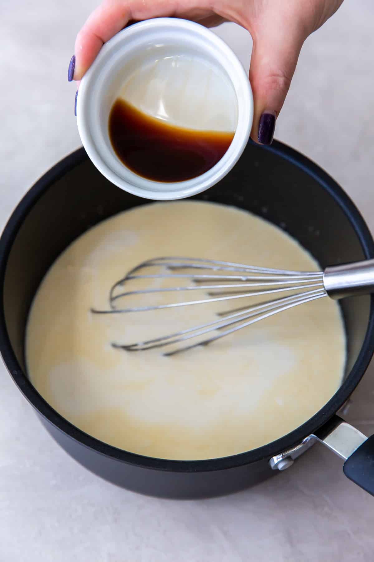 pouring vanilla extract into a saucepan
